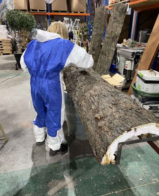 a woman working on an artificial tree trunk
