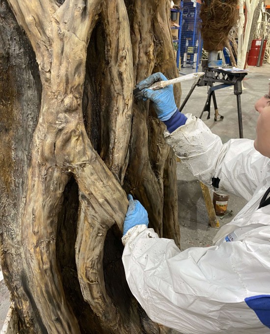 a women applying paint to a bespoke artificial tree trunk